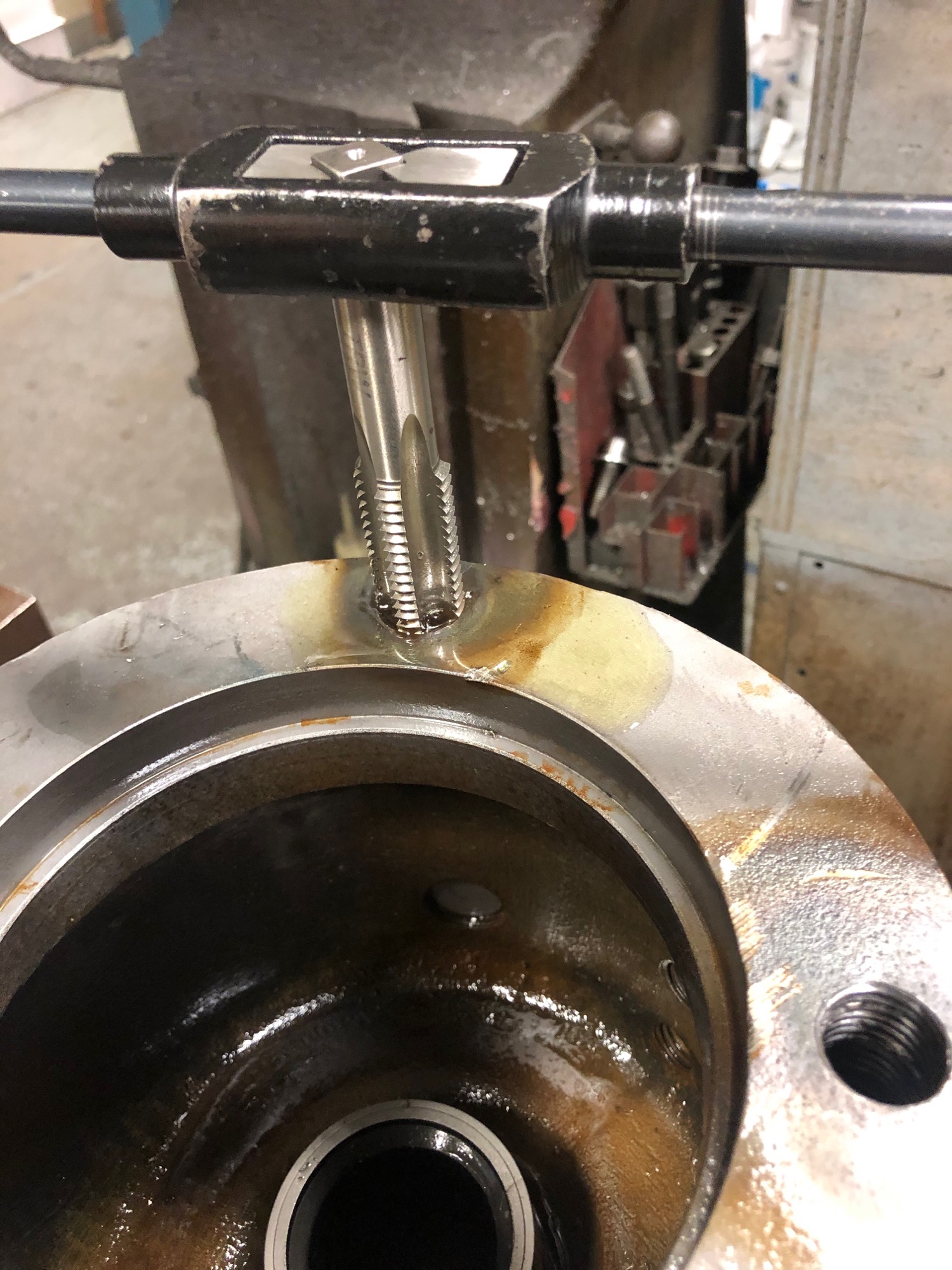 Damaged industrial threads being restored with a tap